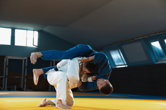 dois jovens judocas de quimono treinando artes marciais no ginasio com expressao em acao e movimento