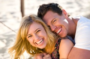 Happy couple embracing and laughing on the beach