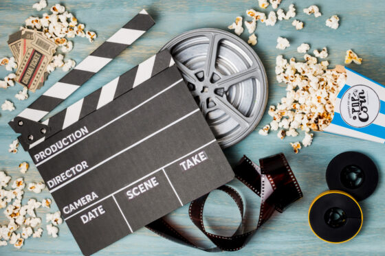 clapperboard popcorn film stripe and cinema tickets on wooden desk